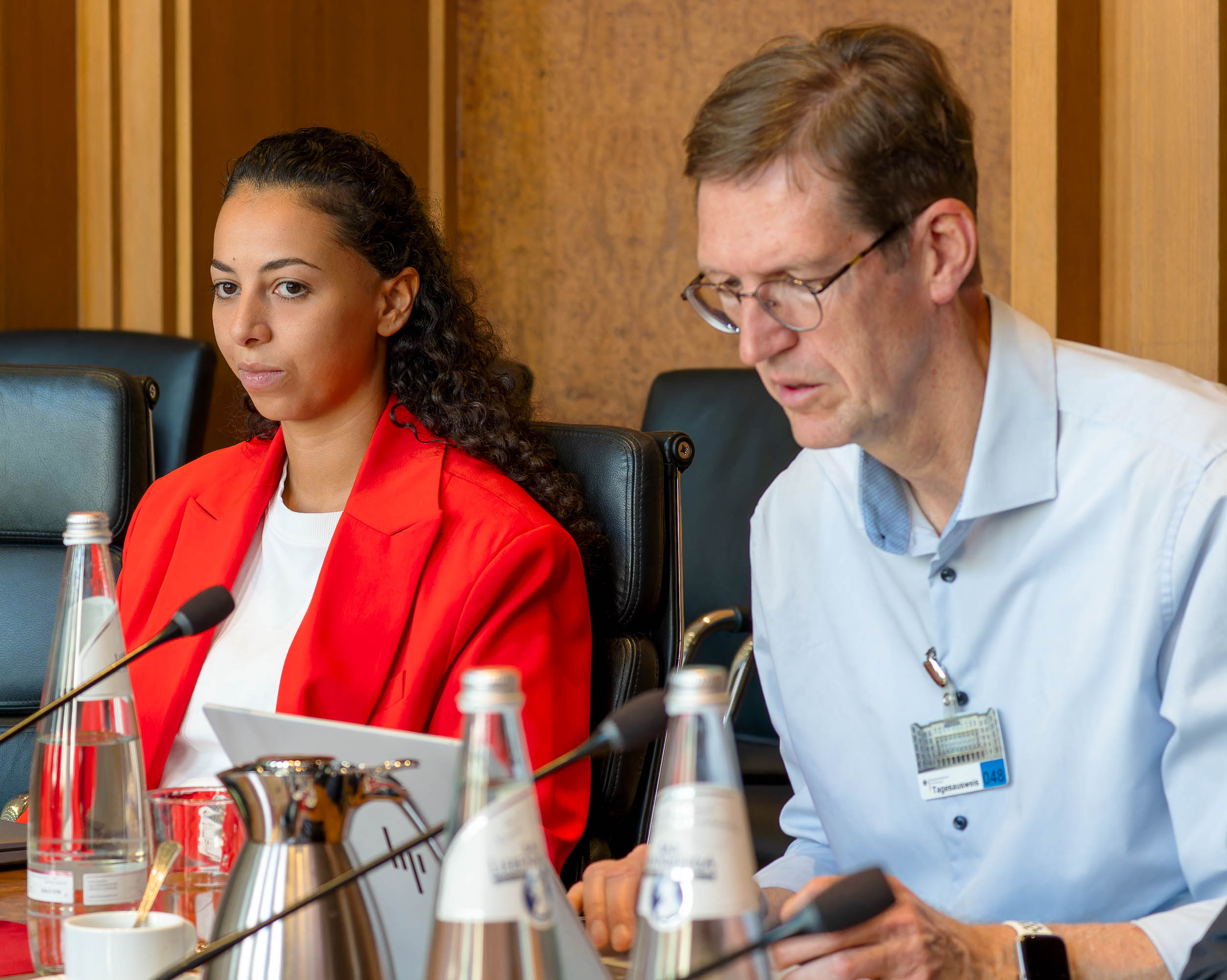 Eine junge Frau sitzt neben einem mittelalten Mann beim Bund-Länder-Treffen im BMF.
